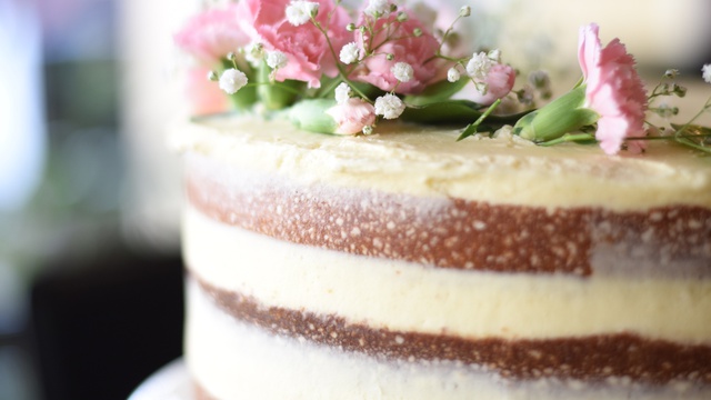 Sandwiched layers of white icing on top of brown butter cake topped with flowers
